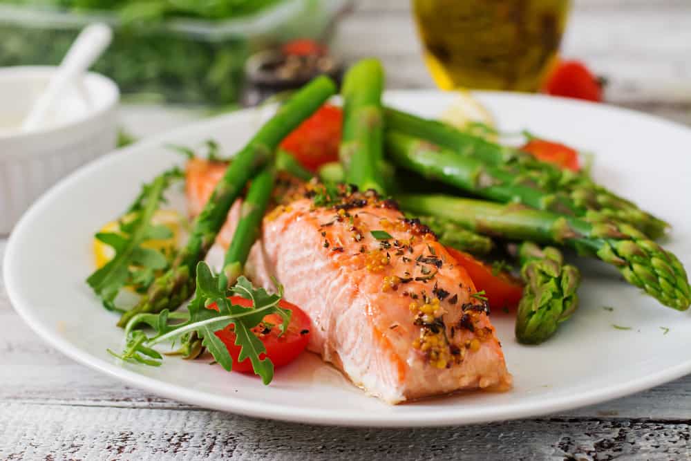 baked salmon garnished with asparagus tomatoes with herbs